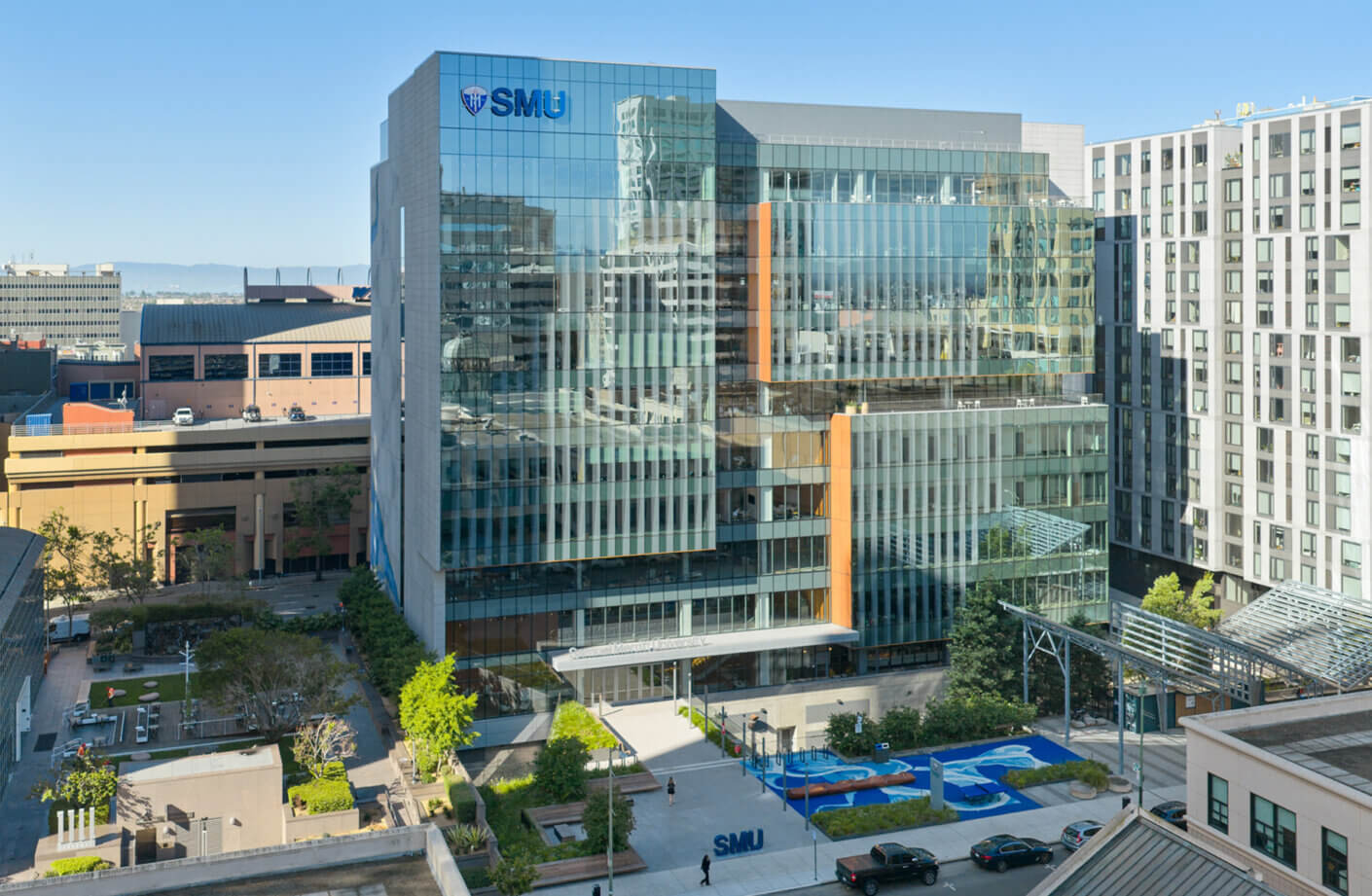 View of the SMU campus building featuring glass facades, landscaped areas, and adjacent structures in an urban setting.