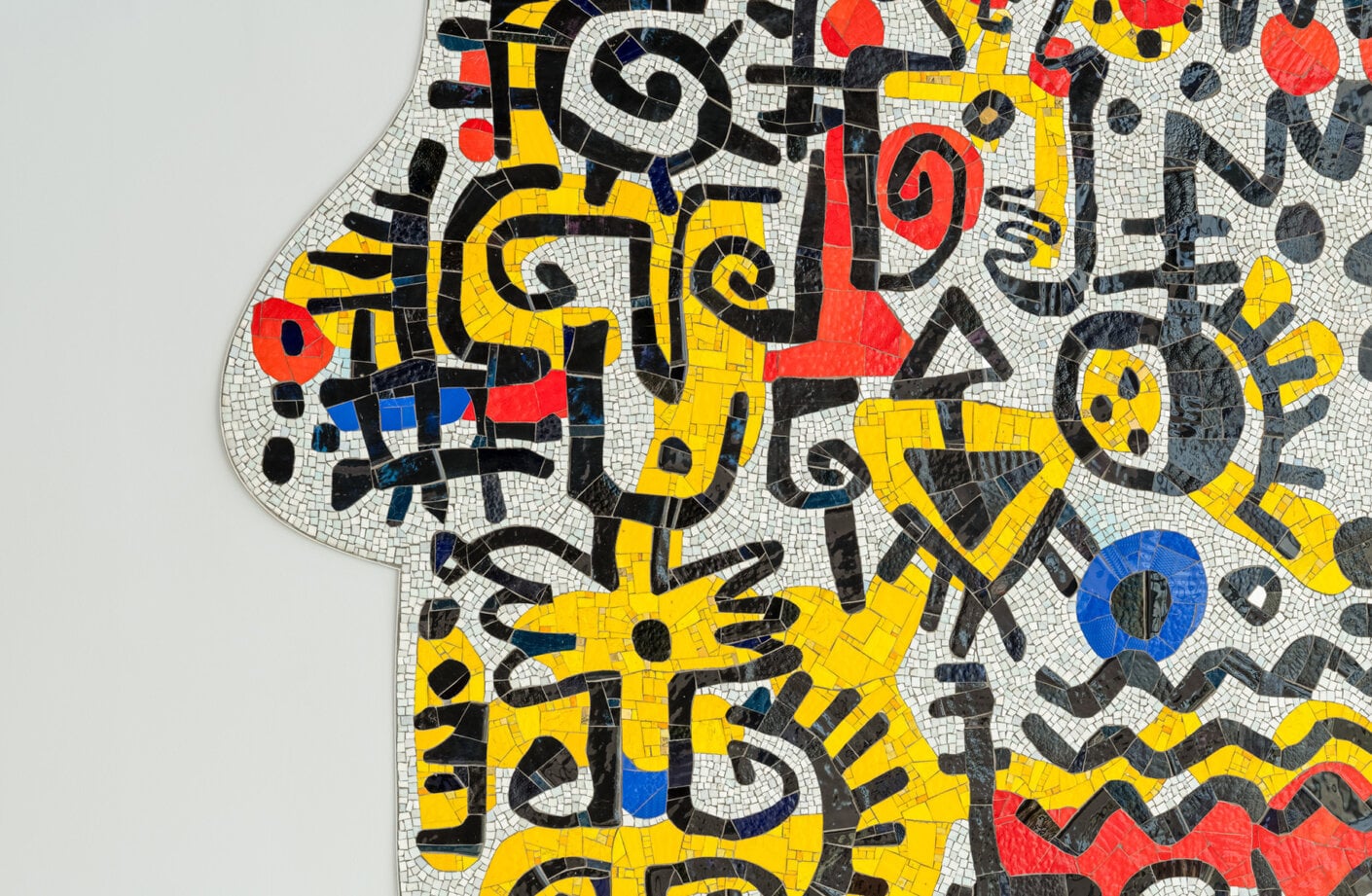 Colorful mosaic artwork featuring abstract shapes and patterns in yellow, black, red, and blue on a white background.