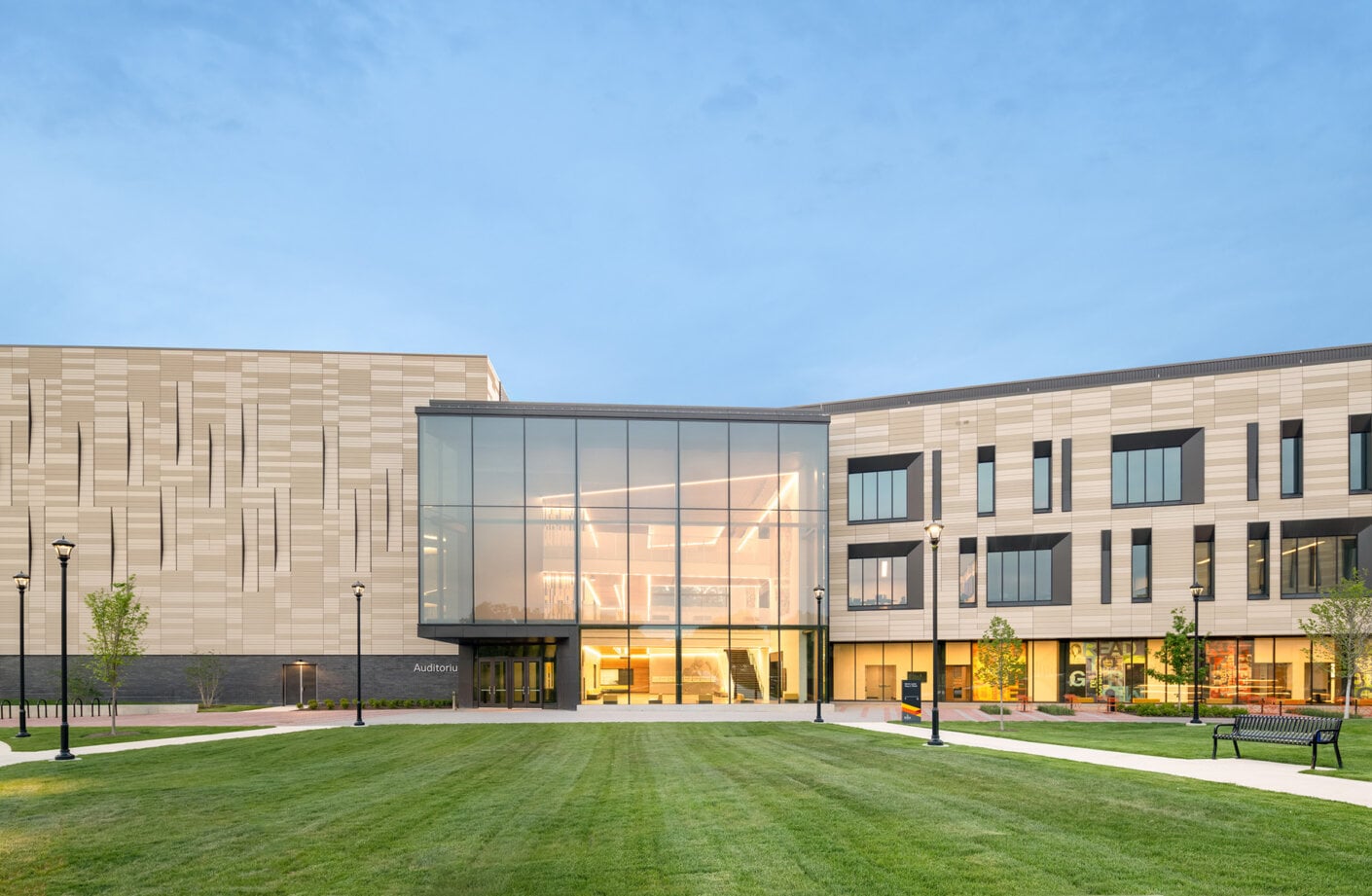 New educational building featuring glass entrance, landscaped lawn, and unique exterior design. Pathways and lighting enhance the accessibility.